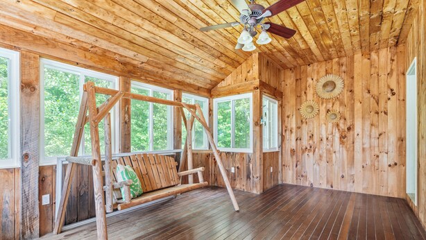 A wooden cabin interior with a swing set, large windows, and a ceiling fan. - Hera Haven: Pickleball, hot tub, racetrack & lake (Stillwater)