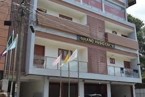 A building with a sign reading 'GRAND RESIDENCY' and multiple flags. - Grand Residency & Resort (Varkala)