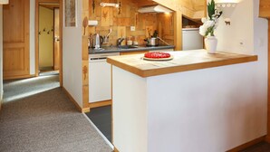 Een moderne keuken met houten balken, een centraal eiland en een kleine koelkast.