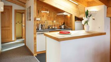 Eine moderne Küche mit Holzbalken, einer zentralen Kochinsel und einem kleinen Kühlschrank.