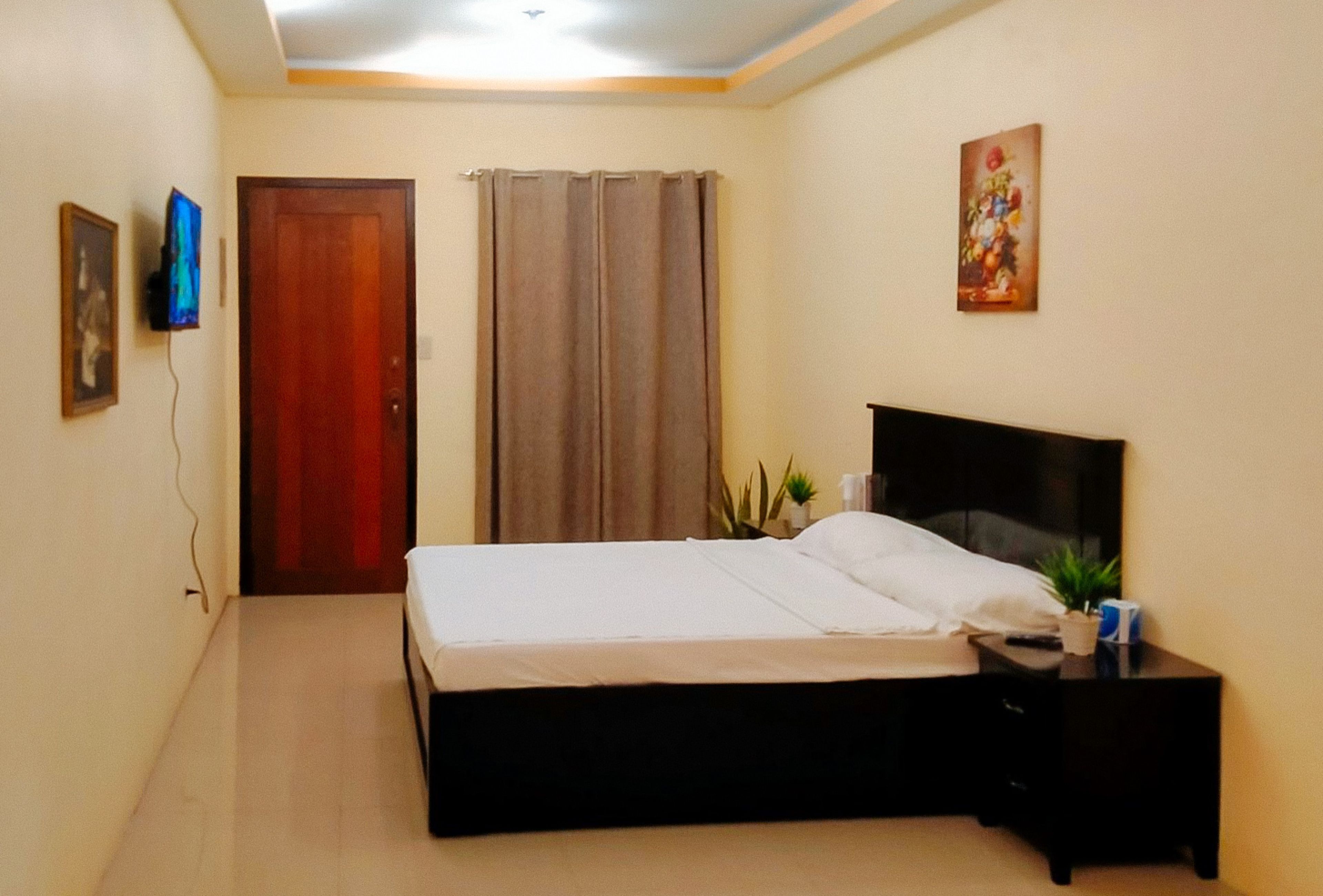 A bedroom with a bed, a nightstand, a television, and a door.