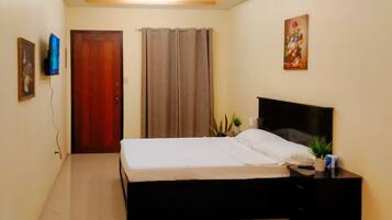 A bedroom with a bed, a nightstand, a television, and a door.
