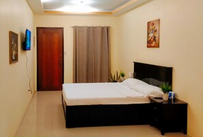A bedroom with a bed, a nightstand, a television, and a door.