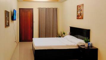 A bedroom with a bed, a nightstand, a TV, a door, and a painting on the wall.