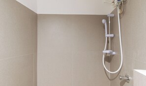 Une douche équipée d’un flexible et d’un robinet fixé au mur.