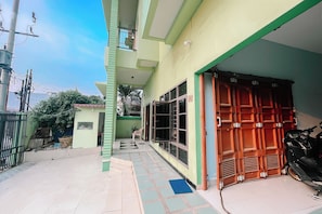A residential building with a covered porch, a gated entrance, and a motorcycle parked outside. - Staigo at SG Premium (Medan)