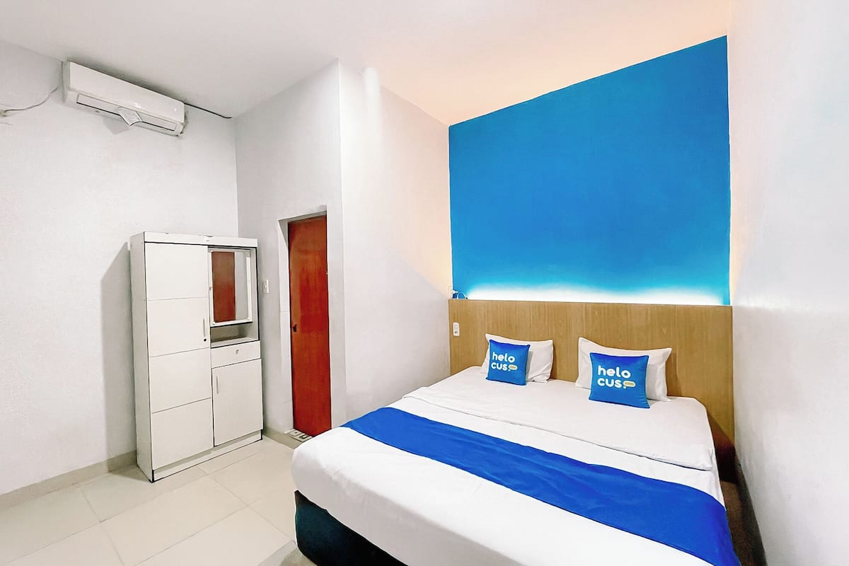 Une chambre d’hôtel équipée d’un lit, d’une armoire et d’un climatiseur fixé au mur.
