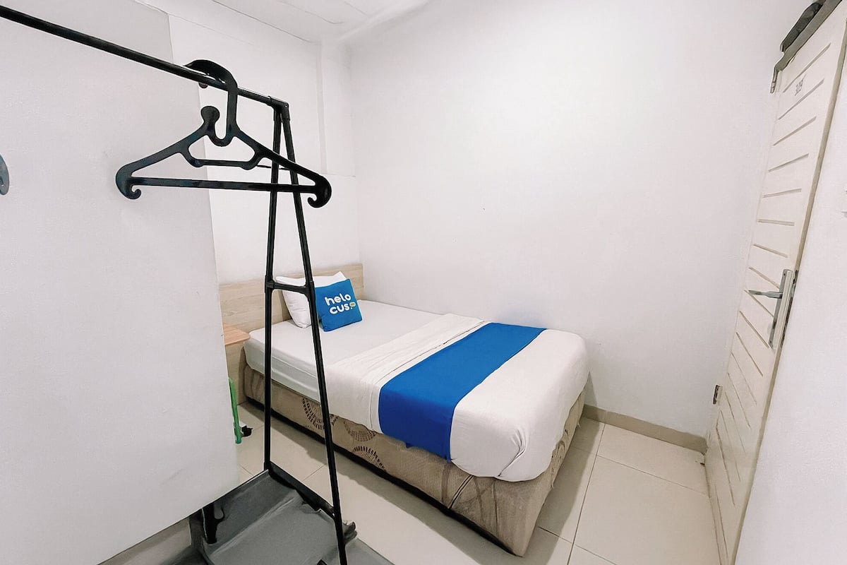 Une petite chambre avec un lit simple, un porte-vêtements et une armoire.