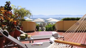 Eine Dachterrasse mit Liegestühlen, einer Hängematte und Topfpflanzen.
