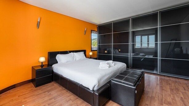 Ein modernes Schlafzimmer mit einem großen Bett, einer Bank und einem Schiebe-Glas-Schrank.