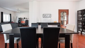 Ein Essbereich mit einem schwarzen Tisch und Stühlen, einem schwarzen Schrank mit Gläsern sowie einer Holztür mit Fensterfeldern.