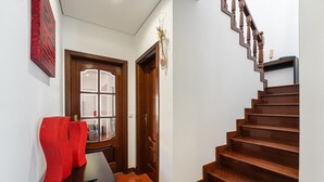Ein Flur mit einer Holztreppe, einer Glastür und einem roten Blumenvasen auf einem Tisch.