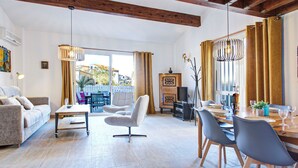 A spacious living room with a sofa, armchairs, a dining table set for four, and a balcony with a view. - Villa 12 Cassin by Interhome (Canet-Plage)