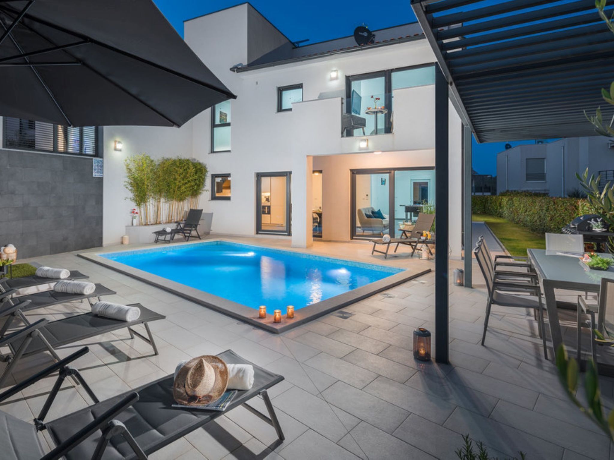 Une maison moderne dotée d’une piscine, d’un espace salon extérieur et d’un patio couvert.