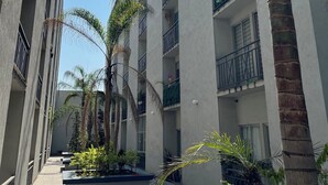 A multi-story building with balconies, palm trees, and a clear sky.
