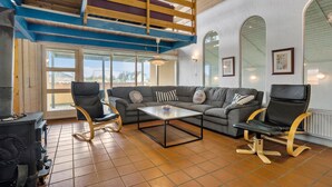 A spacious living area with a high ceiling, a built-in wooden staircase, a large window, and a fireplace. - Pet friendly home in Thisted with sauna (Thisted)