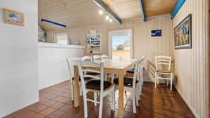 A dining area with a wooden table and white chairs, a kitchen area with a window, and a view of the outside. - Pet friendly home in Thisted with sauna (Thisted)