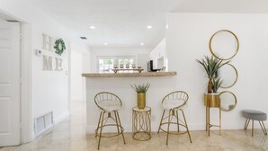 A modern kitchen with a marble countertop, two gold wire chairs, a gold vase, and a potted plant. - Stunning Home with a HEATED POOL 4 miles to the beach! (Pompano Beach)