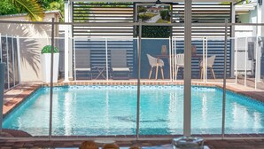 A swimming pool with a tiled deck, surrounded by a fence and chairs. - Stunning Home with a HEATED POOL 4 miles to the beach! (Pompano Beach)