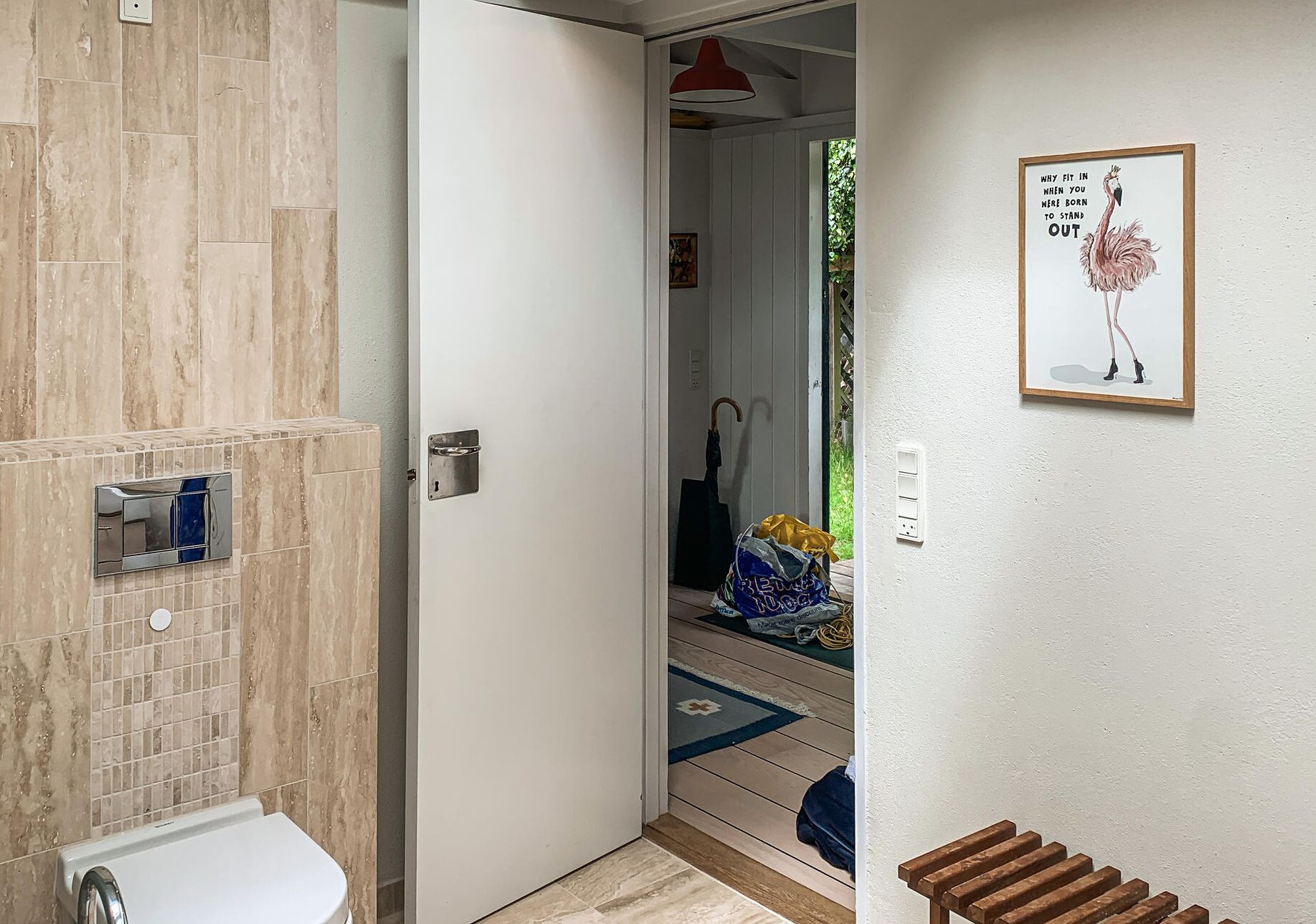 Une salle de bain avec un mur recouvert de carreaux, une porte blanche et un tableau encadré accroché au mur.