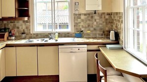 Eine kompakte Küche mit Geschirrspüler, Spüle und einem Fenster für natürliches Licht.