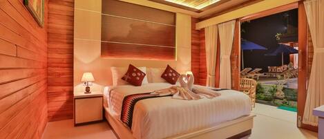 A hotel room with a large bed, a nightstand, a wall-mounted TV, and a view of the outdoor area.