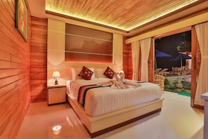Ein Hotelzimmer mit einem großen Bett, einem Nachttisch, einem an der Wand befestigten Fernseher und Blick ins Freie.