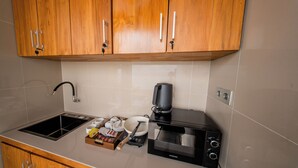 A kitchenette with a microwave, coffee maker, and a kettle. - Sunrise Cottage Penida (Penida Island)
