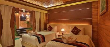 A hotel room with two beds, a wooden ceiling, and a view of the outside.