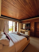 Habitación de hotel con una cama grande, un escritorio con televisor y vista a la playa.