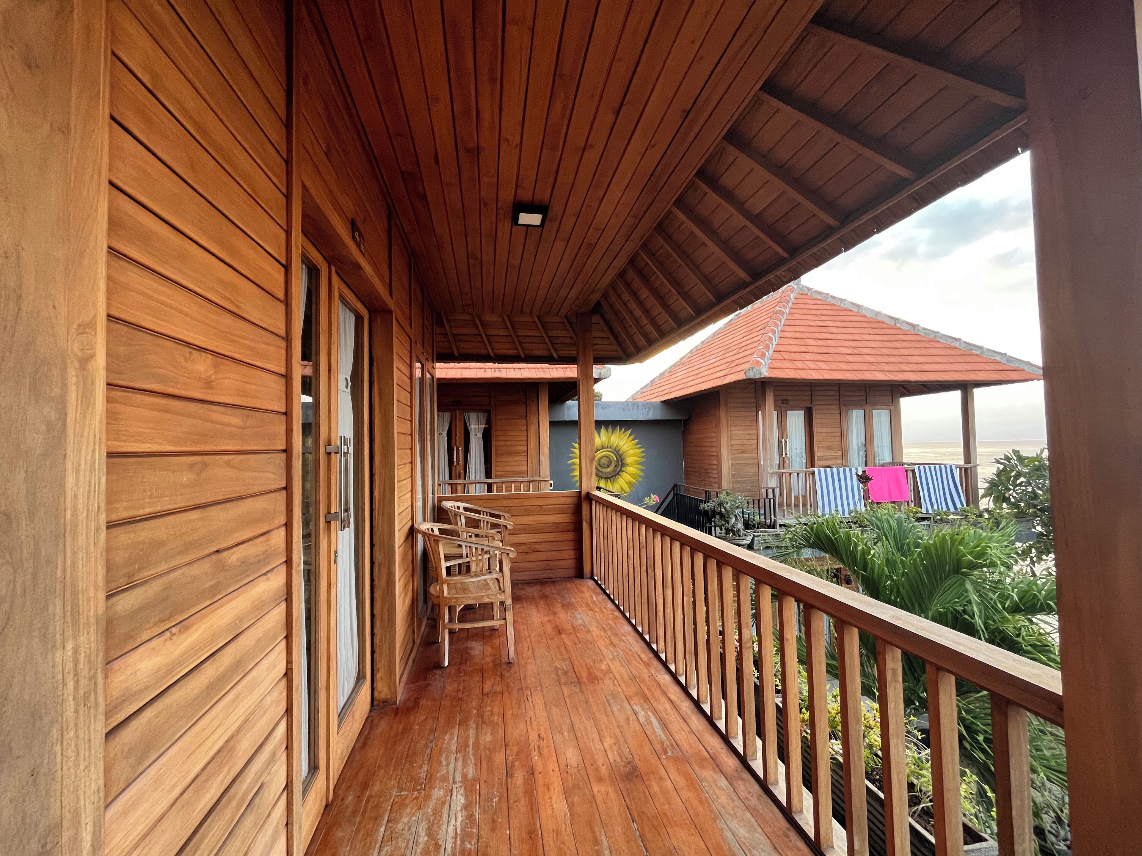 A wooden balcony with a wooden railing, a wooden floor, and a view of the beach.