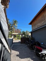 Una calle estrecha con una entrada porticada, motocicletas estacionadas y un edificio con techo de paja.