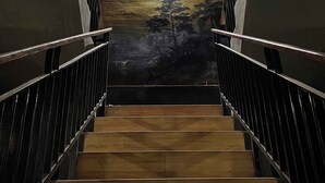 En trappe med gelændere af metal, der fører op til et muralmaleri af et solnedgangsmotiv.