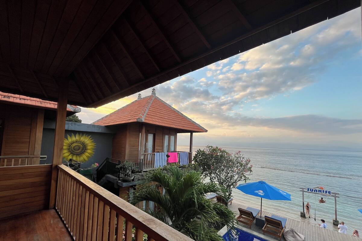 Une terrasse en bois avec une piscine, offrant une vue sur l’océan.