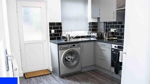 A compact kitchen with a washing machine, a sink, and a stove. - Stoke House Sleeps 5 with Garden and Parking (Stoke-on-Trent)