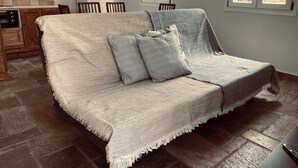 Ett mysigt vardagsrum med en soffa, två kuddar, ett litet bord och ett fönster.