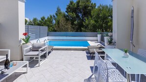 A modern outdoor patio with a swimming pool, white furniture, and potted plants. - Villa Oli/A by Interhome (Medulin/Ližnjan)