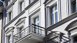 Un edificio de varios pisos con estilo arquitectónico clásico, que presenta ventanas simétricas y barandas de balcón ornamentadas.