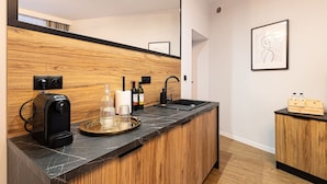 Una cocina moderna con encimera de mármol, cafetera, botellas de vino y un armario de madera.
