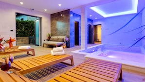 Un moderno espacio de spa con tumbonas de madera, una camilla de masaje y un jacuzzi.