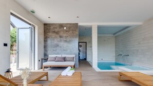 Un spa moderno con un banco de madera, un sofá y una bañera grande.