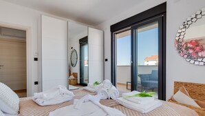 Una habitación de hotel moderna con una cama grande, un balcón con vistas, un espejo y un adorno mural.
