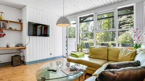 Ein modernes Wohnzimmer mit Glastisch, Ledersofa und Wand-Fernseher.
