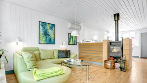 Ein modernes Wohnzimmer mit einem grünen Sofa, Holzboden, einem Kamin und abstrakter Kunst an den Wänden.