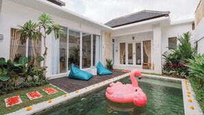 A modern house with a swimming pool, a pink flamingo float, and a wooden deck. - Villa Noni Kerobokan (Seminyak)