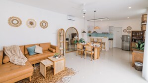 A modern living room with a sofa, coffee table, and dining area. - Villa Noni Kerobokan (Seminyak)