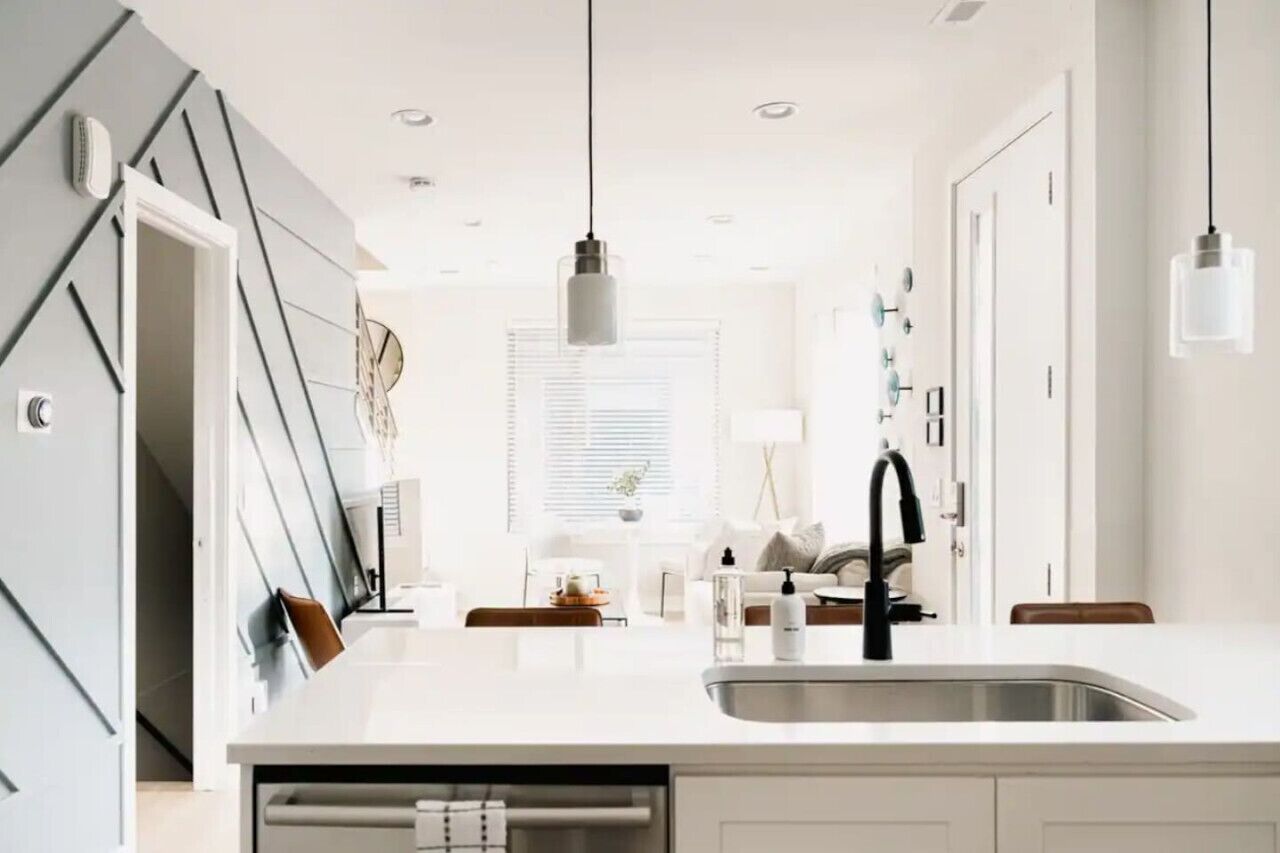 A modern kitchen with a central island, a built-in oven, and a large window.