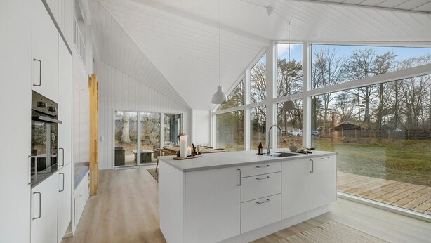 A modern kitchen with large windows, a wooden deck, and a view of the outdoors. - 5 bedroom nice home in Græsted (Græsted)