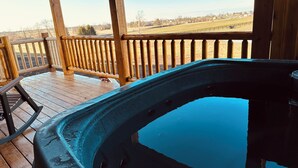 Ein Whirlpool auf einer Holzterrasse mit Blick auf eine ländliche Gegend.