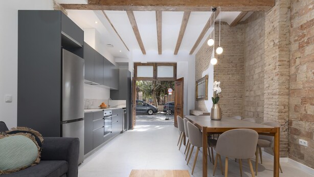 A modern kitchen with grey cabinets, a wooden dining table, and a sofa with a cushion. - My Loft 4 You Patraix Style (Valencia)